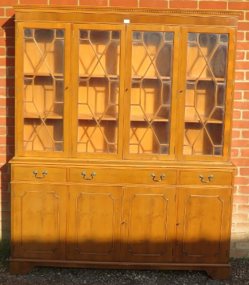 A reproduction yew wood library bookcase, having a dentil cornice above four astral glazed doors,