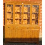 A reproduction yew wood library bookcase, having a dentil cornice above four astral glazed doors,
