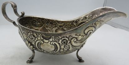 A white metal heavily embossed sauce boat on hoof feet and double scroll handle, probably 1817,