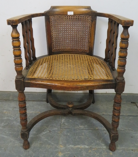 An antique fruitwood Continental bergère tub chair, the curved arms joined by shaped spindles and