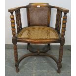 An antique fruitwood Continental bergère tub chair, the curved arms joined by shaped spindles and
