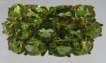 A three row oval faceted peridot ring, width setting 12mm, size N, marked 'sterling'. Approx