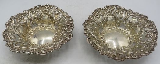 A pair of silver circular bon bon dishes, heavily embossed with scrolls and with pierced decoration,