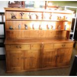 A pine dresser unit, with twin shelved plate rack back, over three inline drawers, and four cupboard