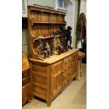 A stripped Ercol oak dresser, with twin shelved plate rack back, over four central drawers flanked b