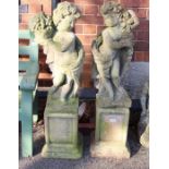 A pair of well weathered garden cherubs on square pedestal plinths. 107 cm high.