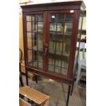 A first quarter 20th century glazed display cabinet having upholstered shelved interior.