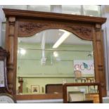 A carved light oak framed arch topped over mantle mirror with grape and vine and half column.