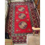 A woven woolen crimson ground floor carpet having three central elephants feet.