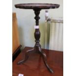 A modern reproduction pie crust edged wine table on three down swept legs.