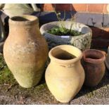 A small cast concrete planter with three terracotta pots.