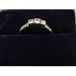 A 9ct white gold diamond ring, set three stones, with three smaller stones inset to the shoulders, g