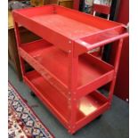A red metal three tier trolley on castors