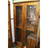 A shelving unit with twin glazed doors and shelved interior in mahogany finished imported hard wood