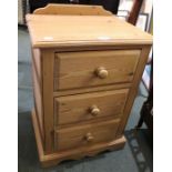 A small pine bedside chest of three drawers.