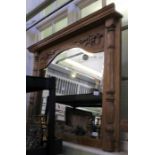 A carved light oak framed arch topped over mantel mirror with grape and vine and half column.