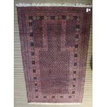 A woven woolen red ground stylised prayer rug.