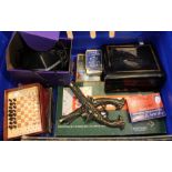 A blue crate principally containing table games and a BT answer phone with hand set.