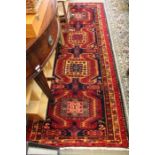 An Azerbaijan woven long rug, four central motifs in a multi-ground border, 290cm x 110cm