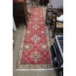 A red ground woven woollen geometric patterned floor runner 93 x 369cm