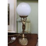 A modern brass table lamp of female form holding aloft a globe