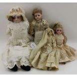 A collection of four early 20th century dolls, some with bisque heads, all dressed.