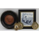 A framed terracotta roundel of a girls face, incised monogram, 9.5cm in diameter