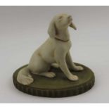 A Royal Dux porcelain seated dog, sporting a pink ribbon, upon a green base, bears factory triangle