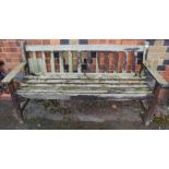 A well weathered teak three person slatted bench.