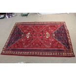 A Persian Shiraz woven woollen carpet, busy blue and red central field 2.95m x 2.10m