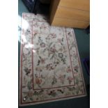 A cream ground rug with floral decoration.