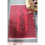 A woven woolen geometric patterned small floor rug.