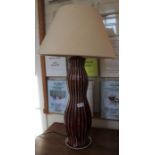 A red glazed ribbed pottery table lamp together with plain shade