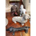Four models of dachshund dogs - two stone examples, one cast iron and the other a wicker effect.