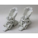 A pair of Continental porcelain ornaments, in the form of Putti in shoes, 14cm