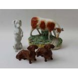 A Victorian Staffordshire pottery cow, 13cm high, together with two Beswick Dachshunds, and a bisque