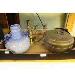 A box of mixed brassware and a decorative blue vase.