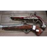 Two reproduction flintlock pistols.