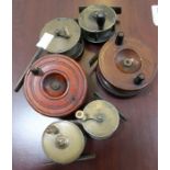 Two wooden fishing reels and four small brass reels with crank handles