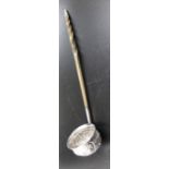 An 18th century silver toddy ladle, with embossed floral decoration, and a twisted whale bone handle