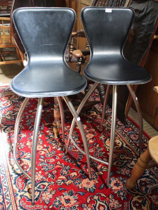 A pair of bar stools, black leather upholstered, swivelling on four leg metal bases