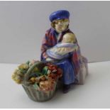 An early Royal Doulton figure group of a female flower seller holding her baby with a basket of flow