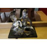 A painted brass Continental figure of a boy & girl sitting on a tree stump