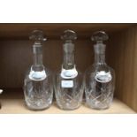 Three matching cut glass decanters with white metal labels