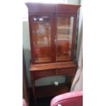 A reproduction yew wood finished display cabinet, on a table base with two inline drawers & an under