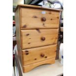 A pine bedside chest of three drawers.
