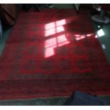 A large sized woven woolen floor carpet of red ground, with multiple central elephants feet, within