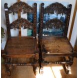 A pair of 17th century design carved oak chairs, scroll carved backs, and plank seats