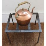 A copper kettle together with a metal trivet