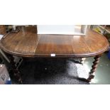 An early 20th century oak wind out dining table with single central leaf supported on four large